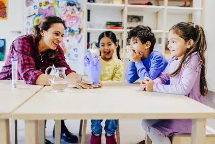 Kinder sitzen am Tisch und beobachten ein Experiment