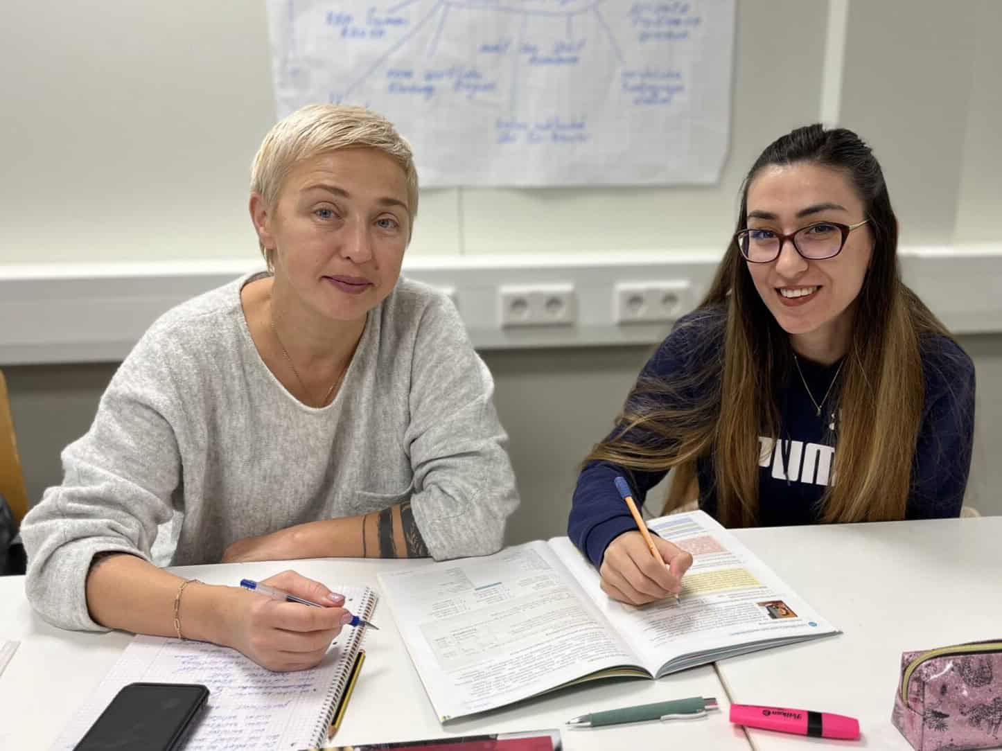 Programm Deutsch 1-2024 Zwei Frauen sitzen an ihren Lernunterlagen