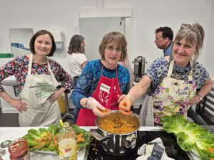 Teilnehmende der Veranstaltung "Kochen für Respekt und Vielfalt" bereiten gemeinsam ein Gericht in der vhs-Küche zu.